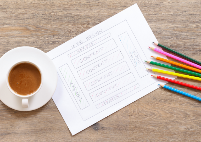 overview of cup of tea, paper with web design sketched out and coloured pencils