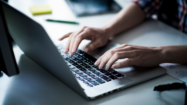 View of hands typing on a laptop