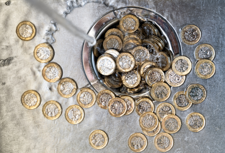coins being washed down the drain to illustrate wasted money