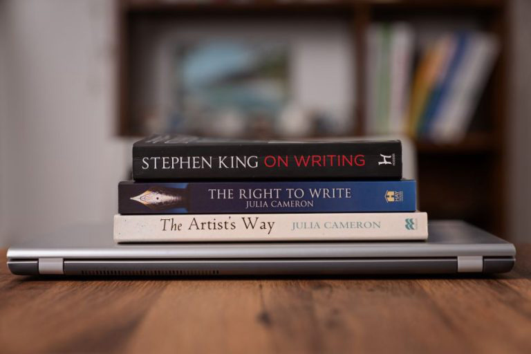 Pile of three books on a laptop related to writing