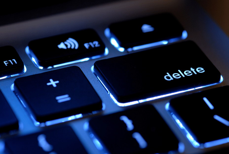 Close up of a keyboard with black keys and bright blue lights and text saying delete